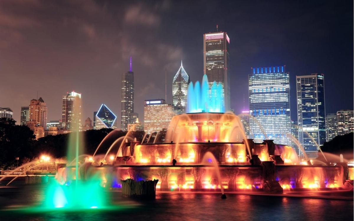 a fountain in front of a city skyline at night