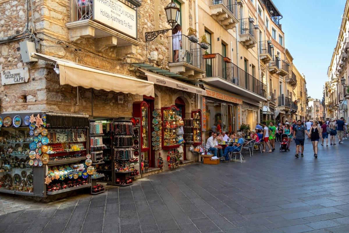 a group of people walking down a street with shops
