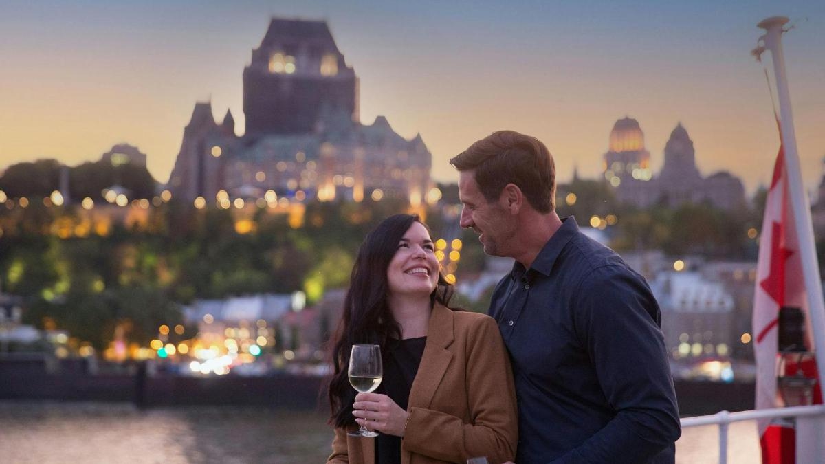 a man and a woman standing on a boat with a glass of wine