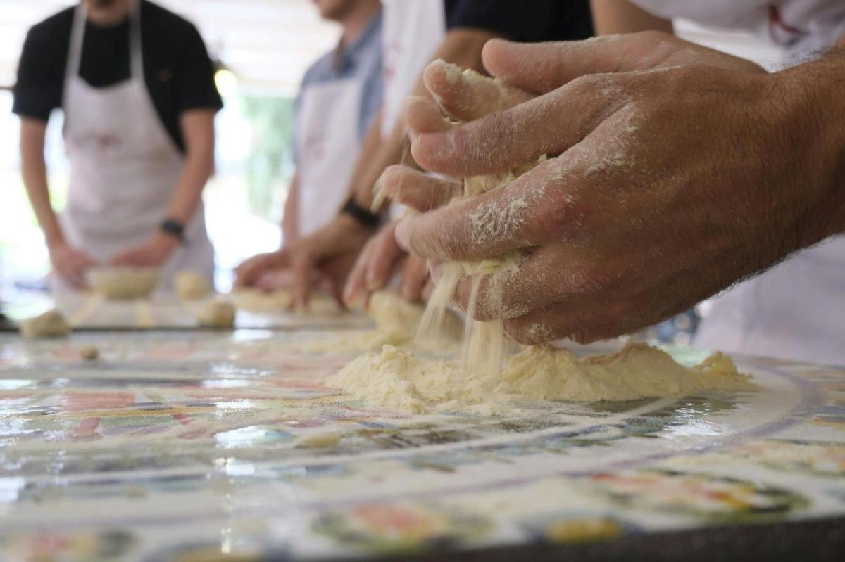 a group of people kneading dough on a table