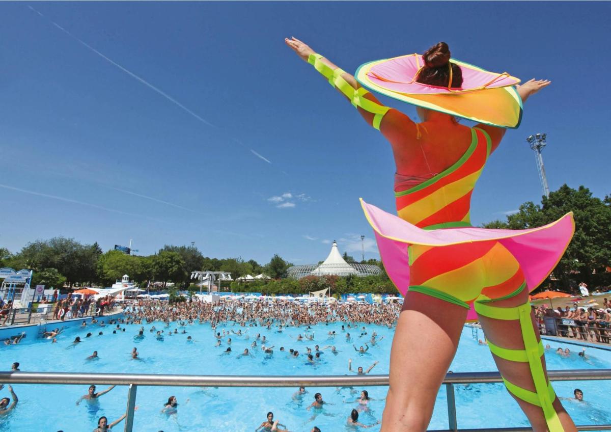 a woman in a swimsuit standing next to a swimming pool