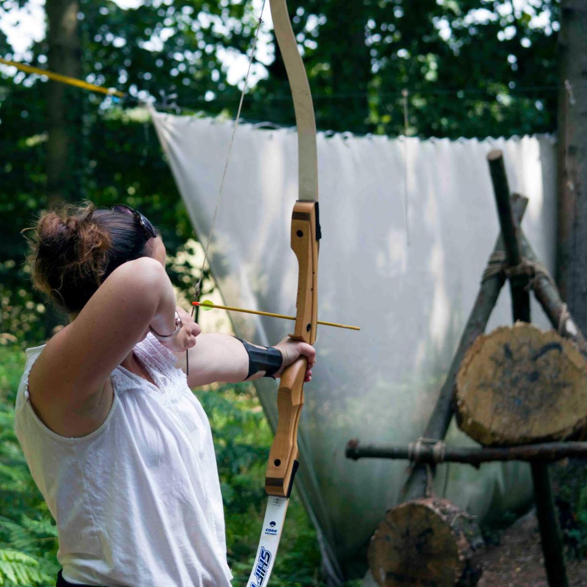 a woman aiming a bow and arrow at a drum