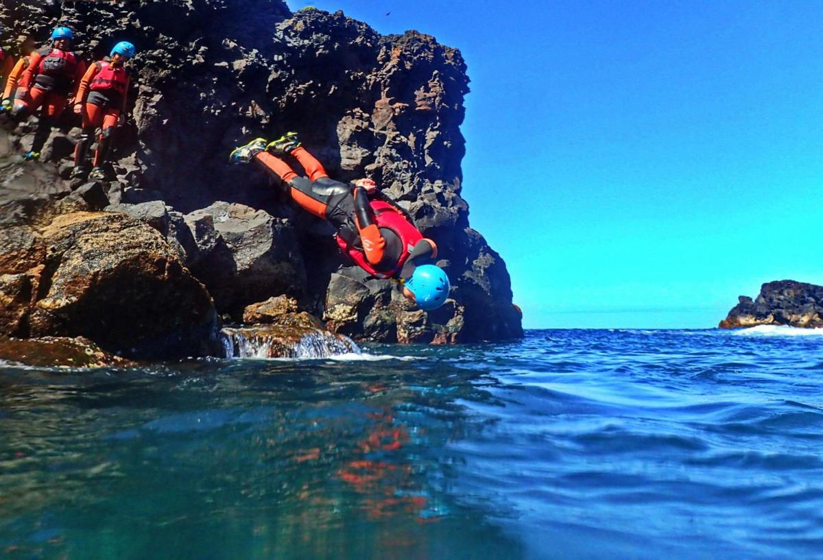 a group of people jumping off a rock into the water