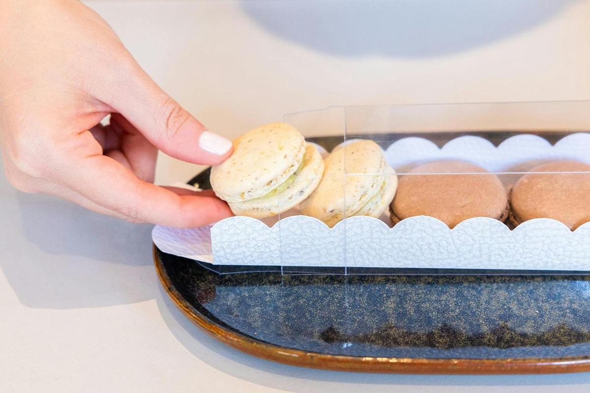 a person holding a sandwich in a tray of buns
