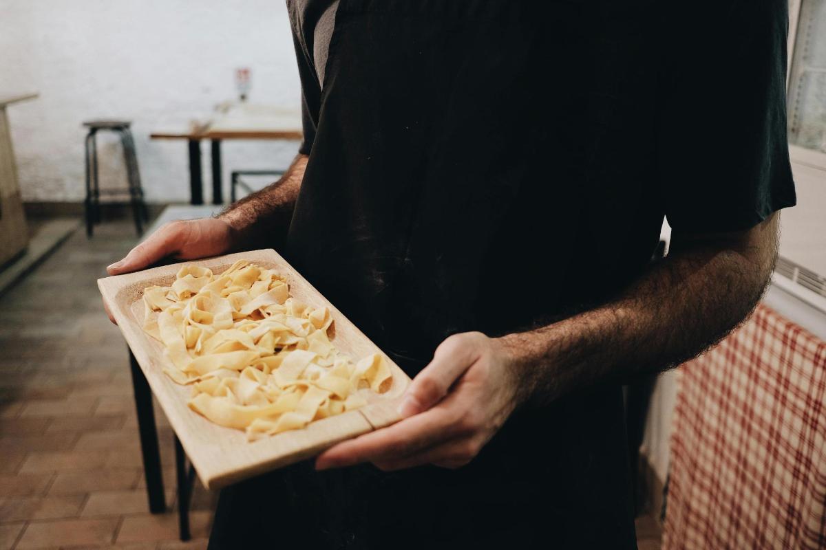 a man holding a cutting board with pasta on it