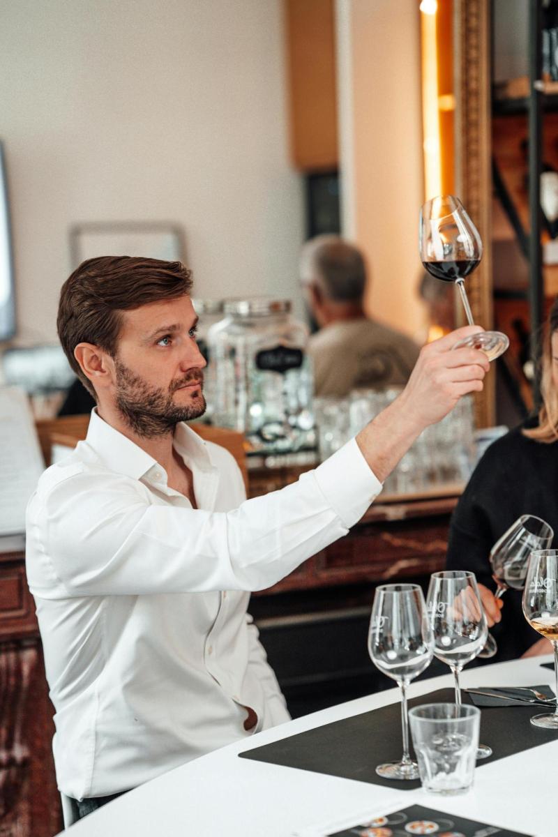 a man holding up a glass of wine at a bar