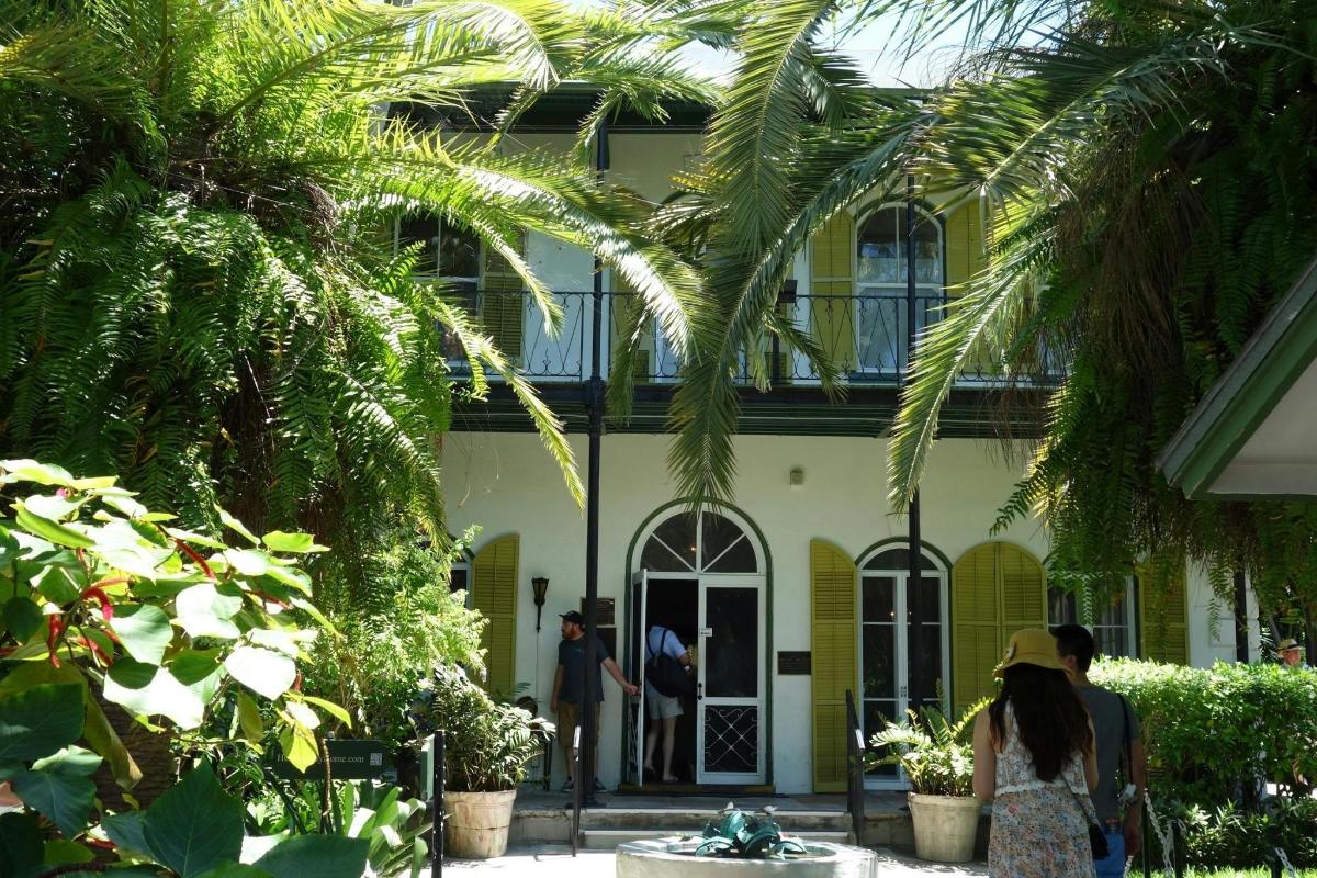 people standing outside of a house with palm trees