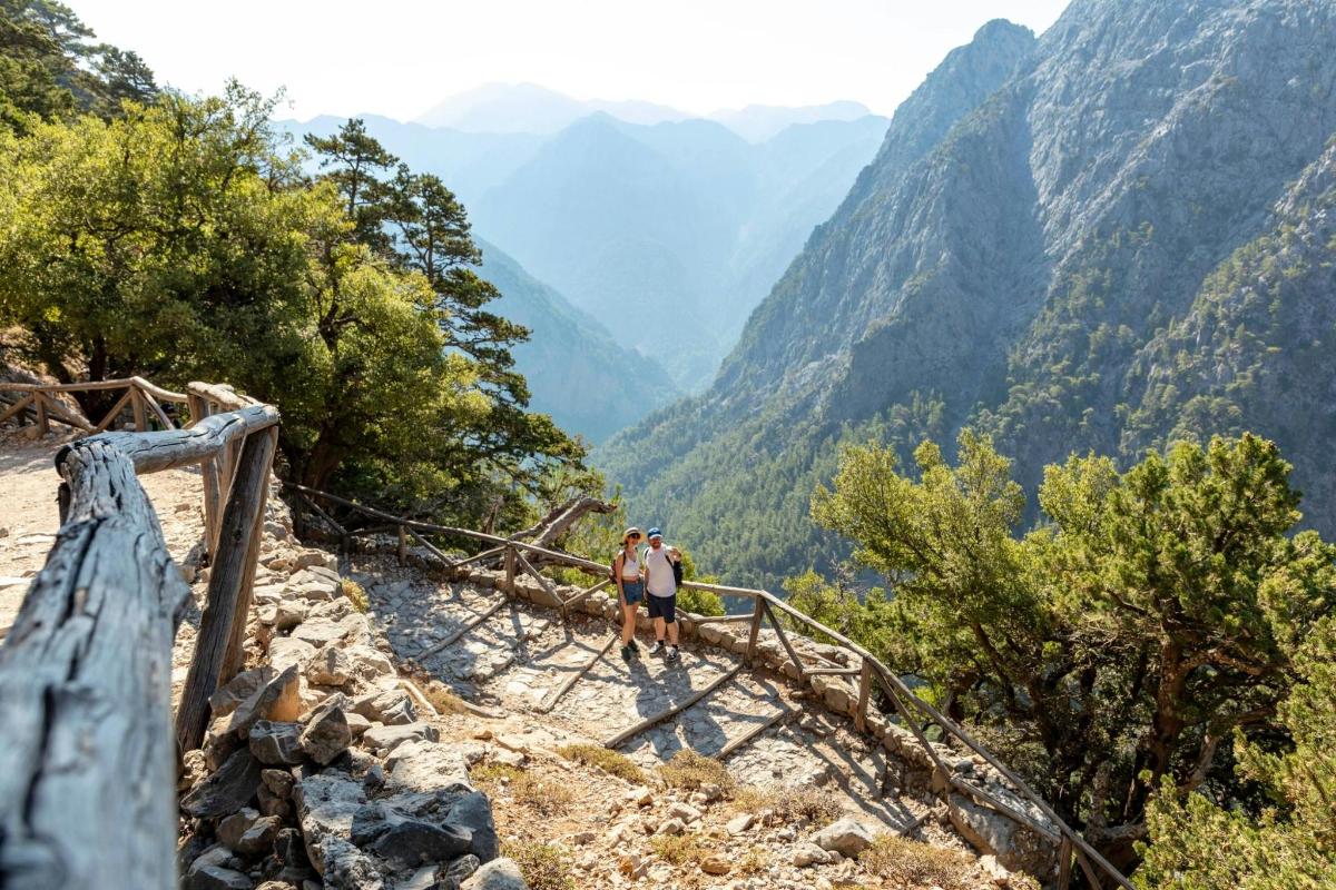 two people walking on a trail in the mountains