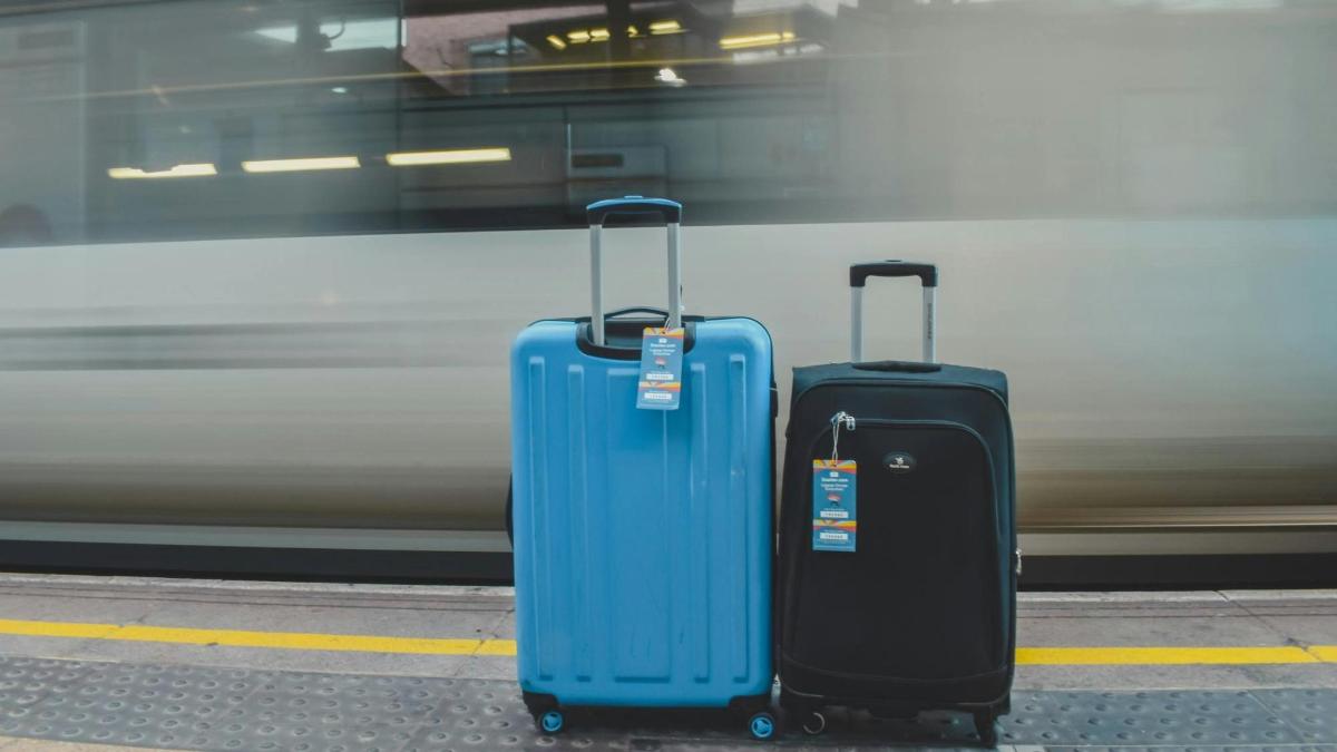 three pieces of luggage sitting next to a train