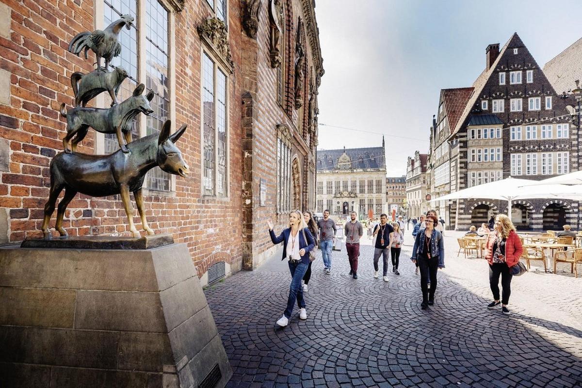 a group of people walking down a street with a statue