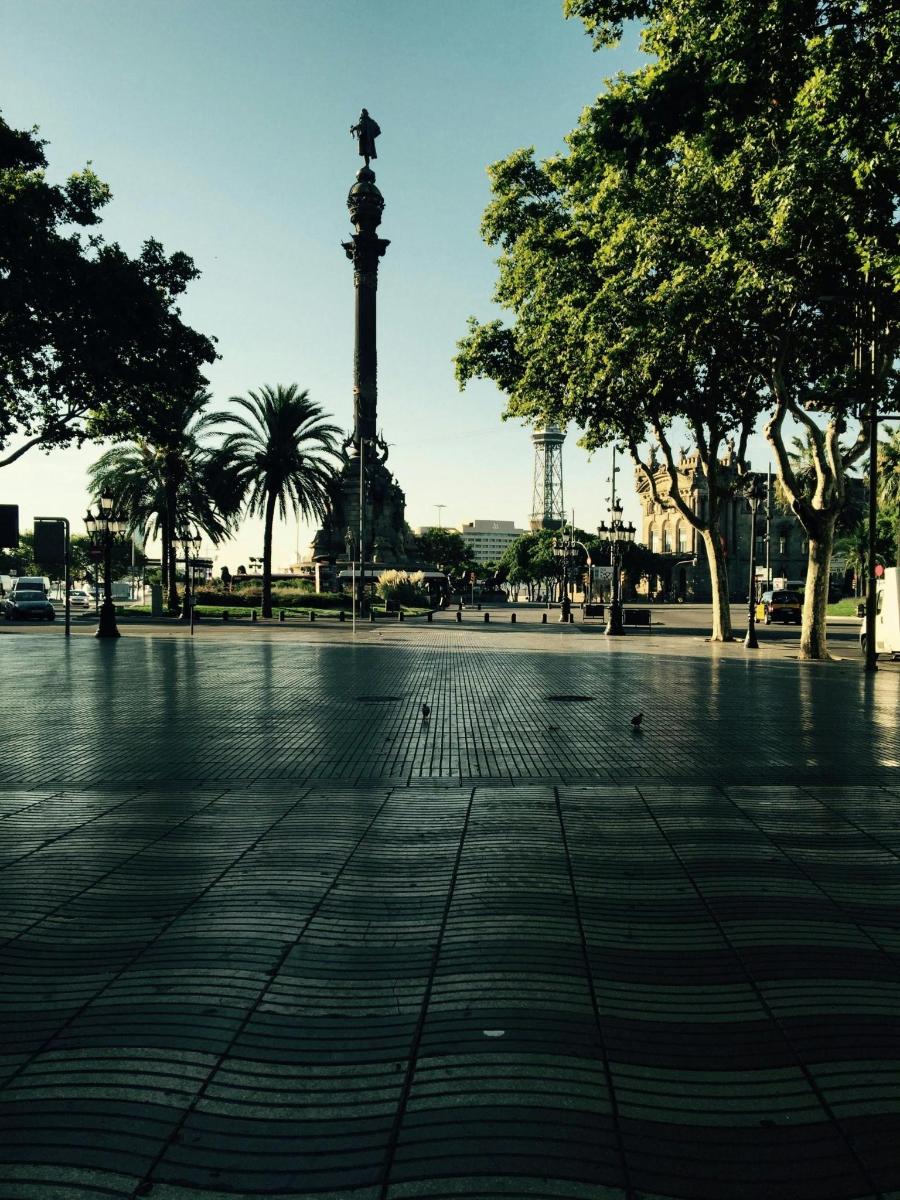 a square with a monument in the background with trees