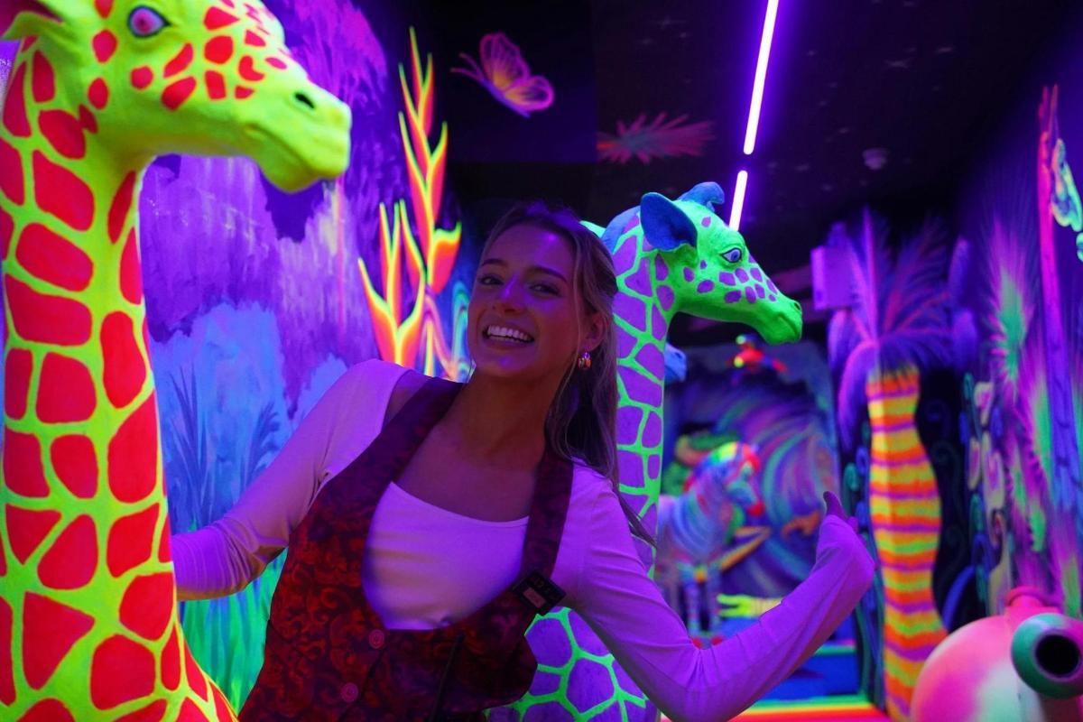 a woman standing next to two giraffes in a room