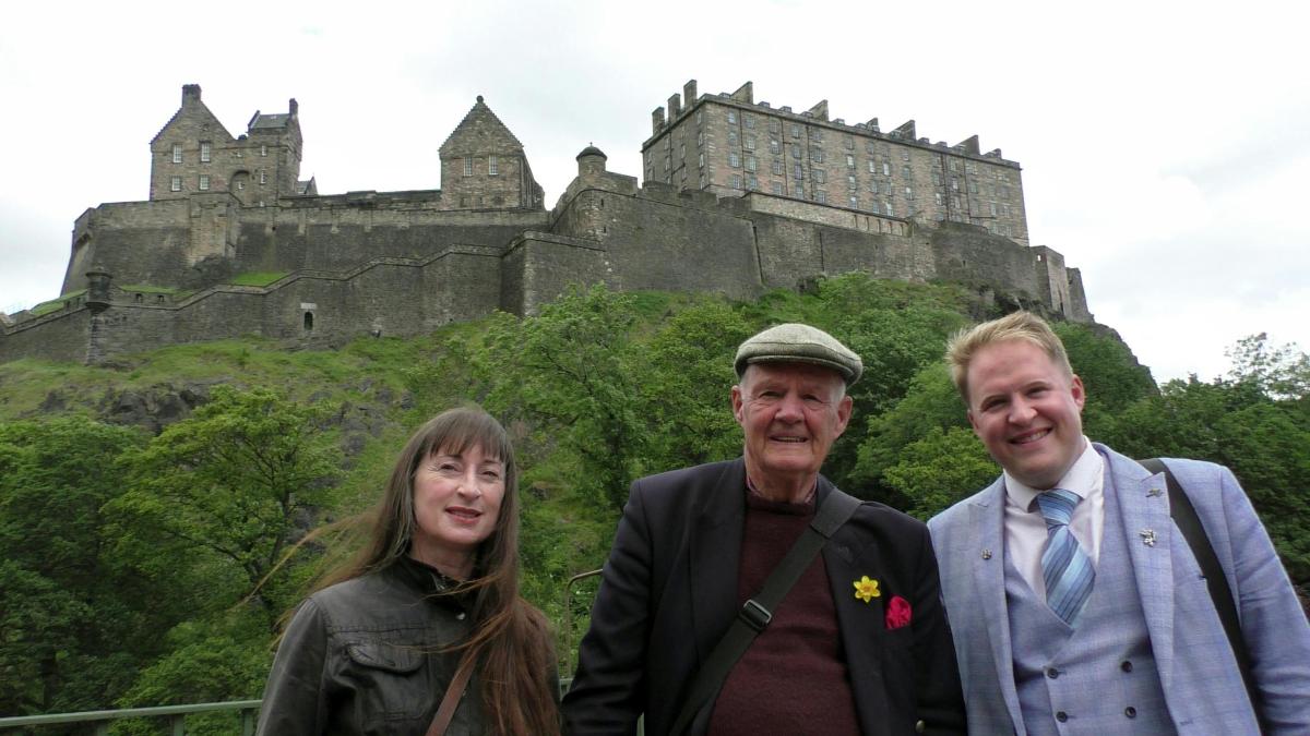 three people standing in front of a castle