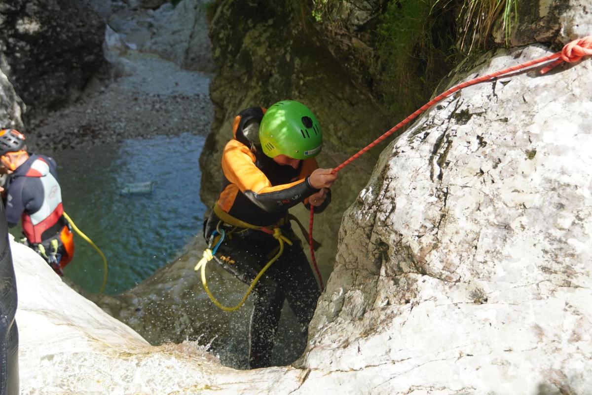 a man in a green helmet rappelling down a rock