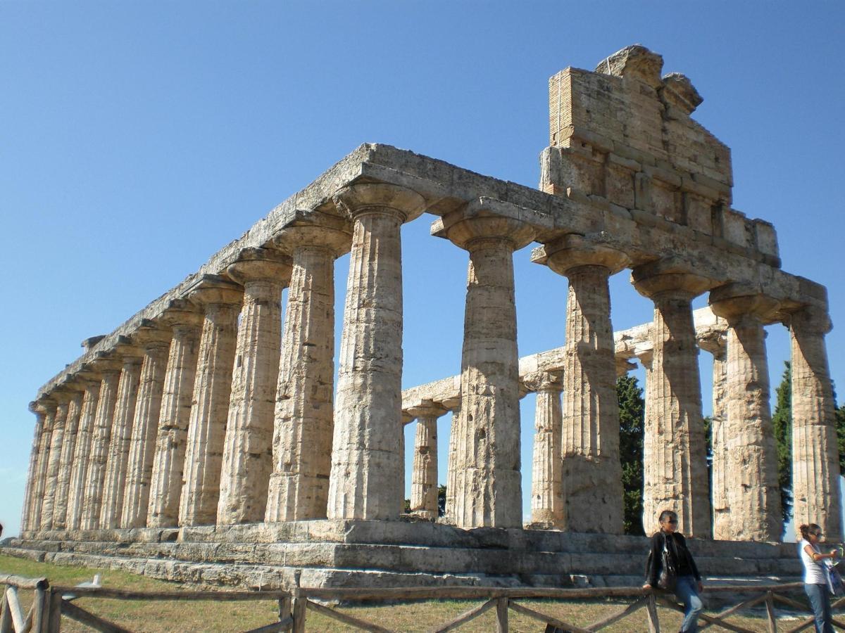 a temple at the acropolis of athens with people walking in front