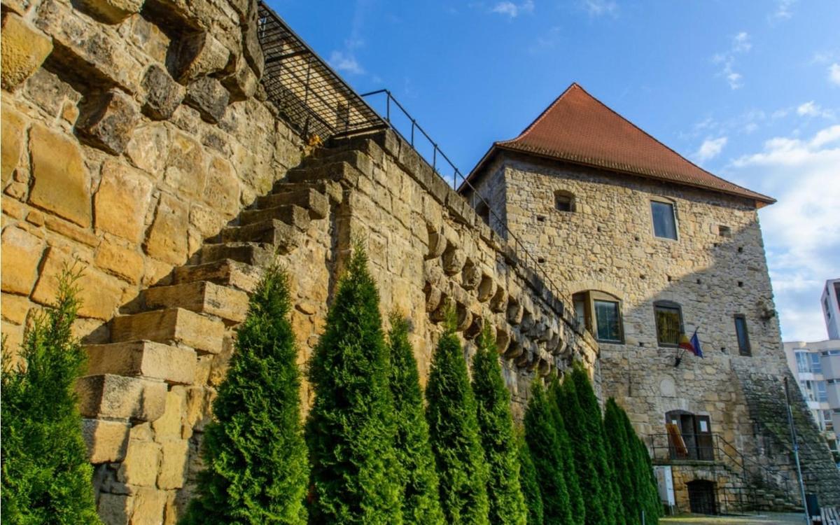 a stone wall with trees next to a building