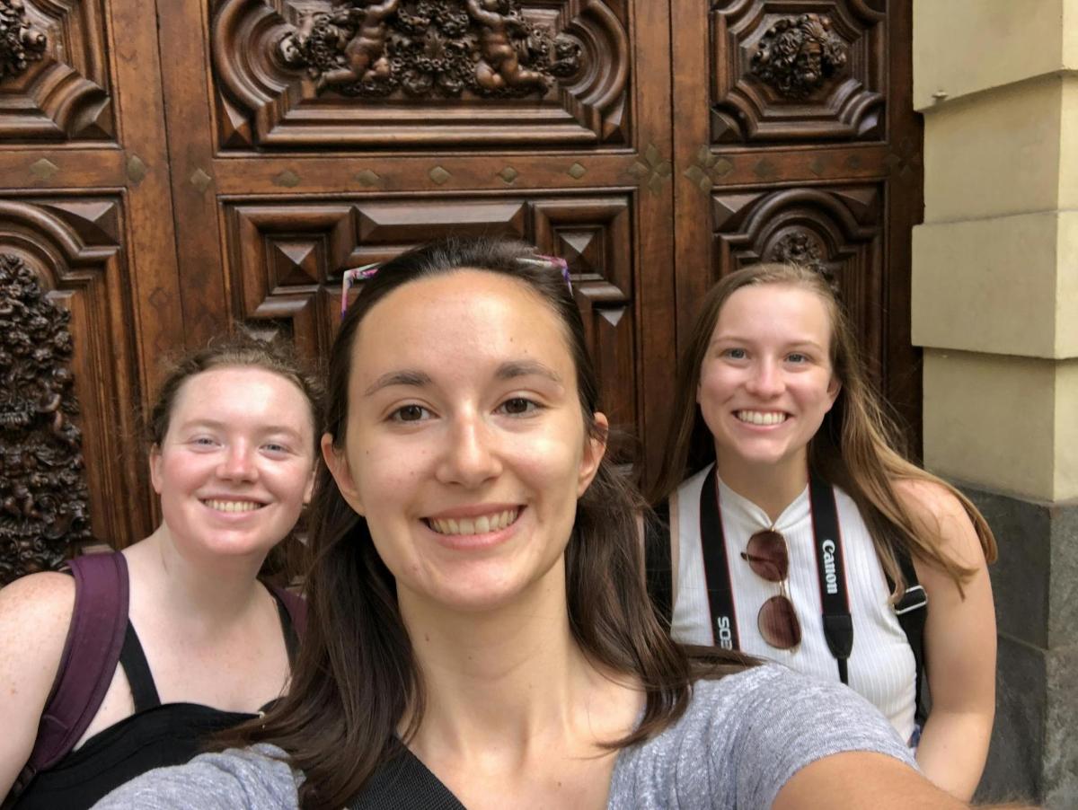 three girls standing in front of a wooden door