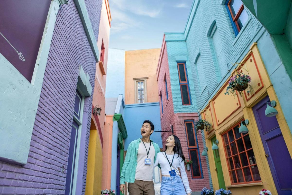 a man and a woman standing in a street of colorful houses