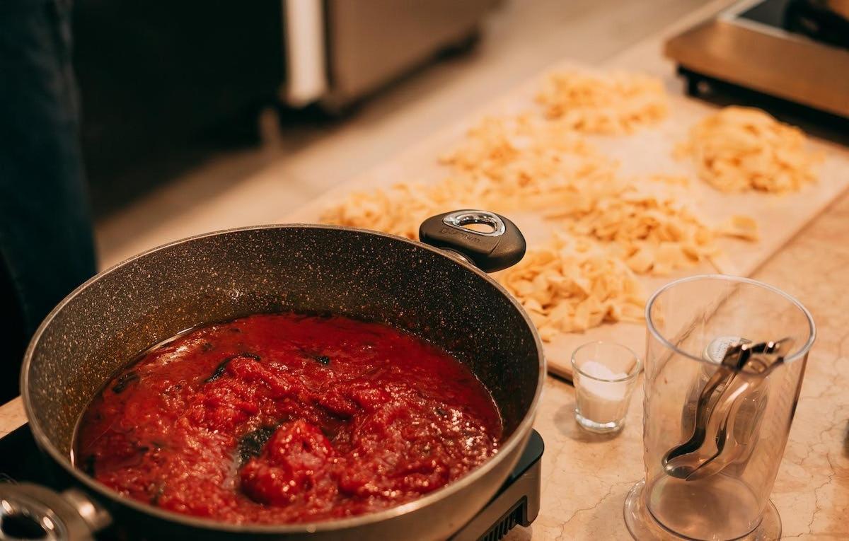 a pot of sauce on top of a stove with pasta