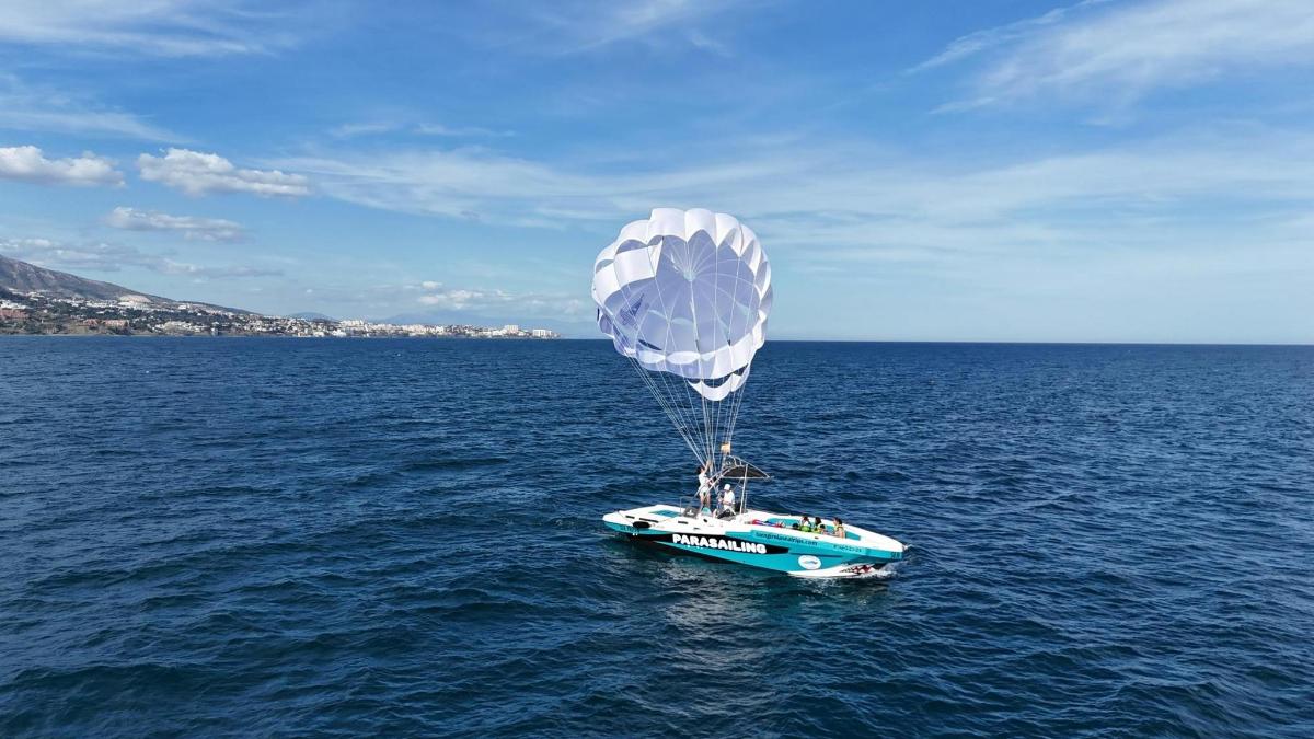 a blue and white boat floating in the water with a parachute