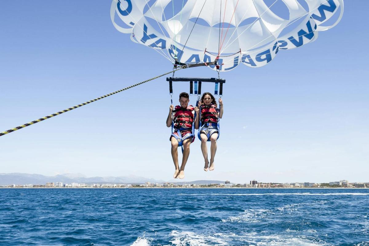 two people riding on a parachute over the water