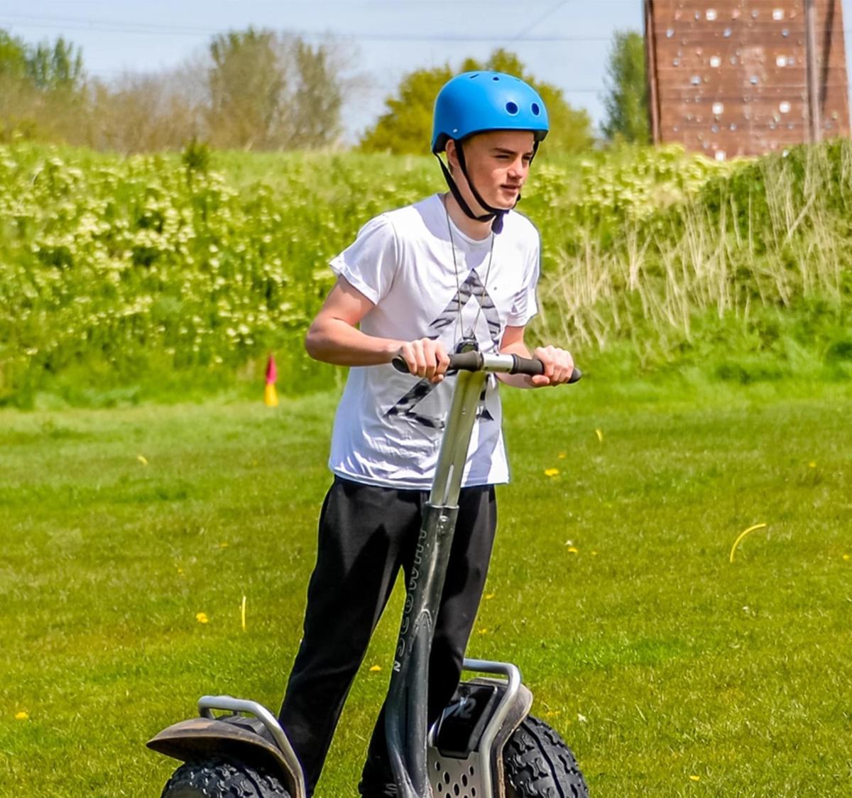 a young boy wearing a helmet riding a scooter