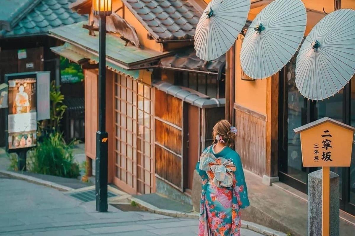 a woman in a dress walking down a street with umbrellas