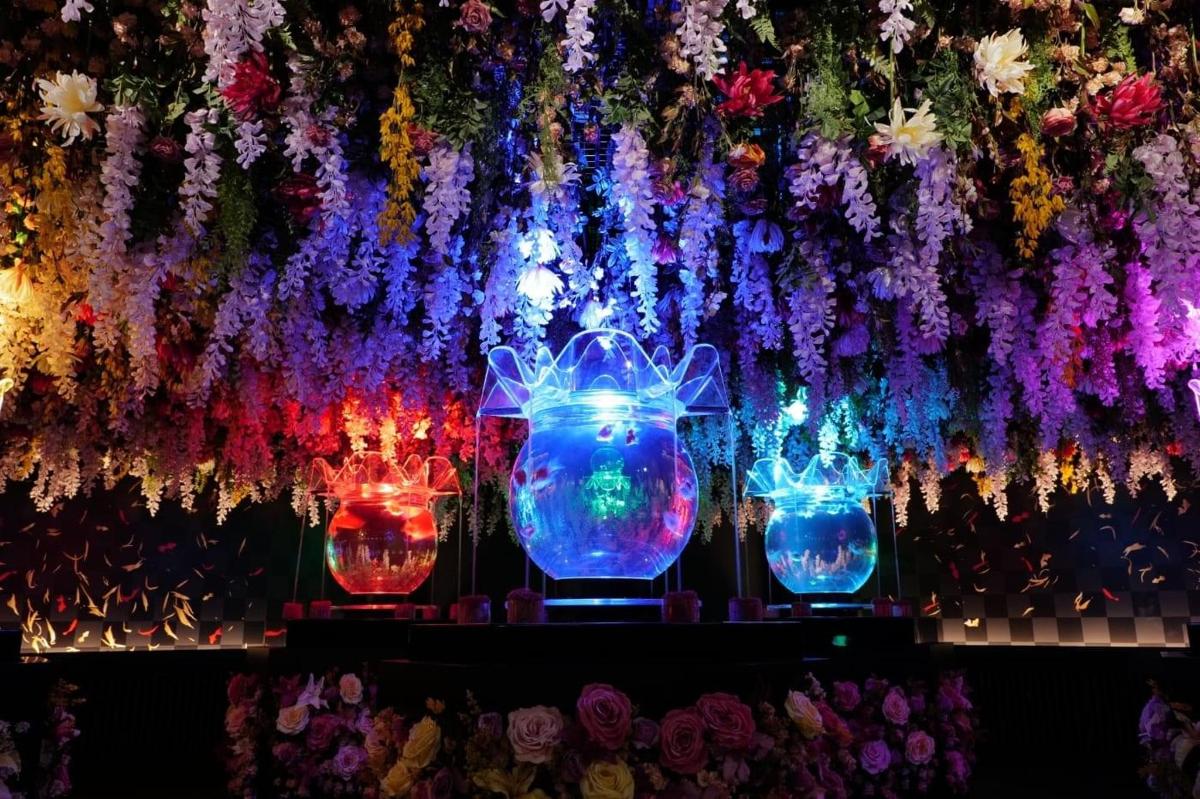 鲜花前摆放着一排色彩缤纷的花瓶。