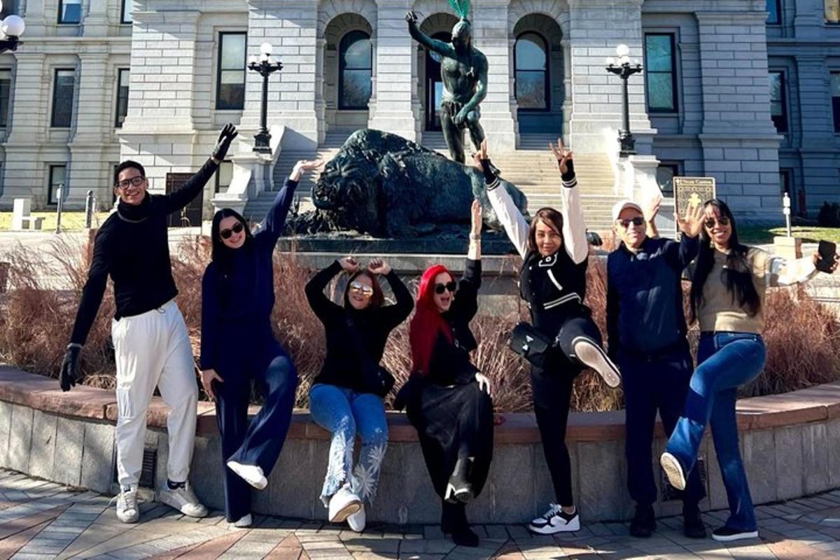a group of people posing in front of a statue