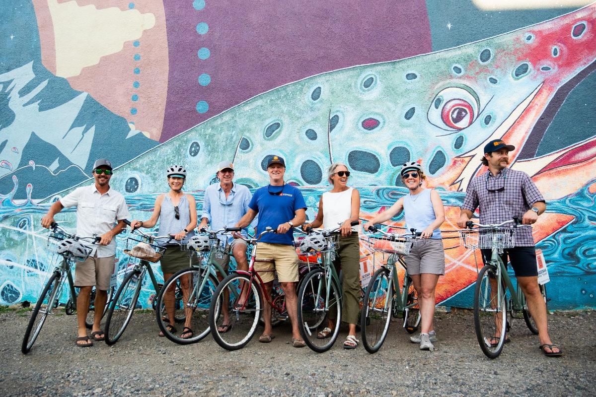 a group of people standing with bikes in front of a wall