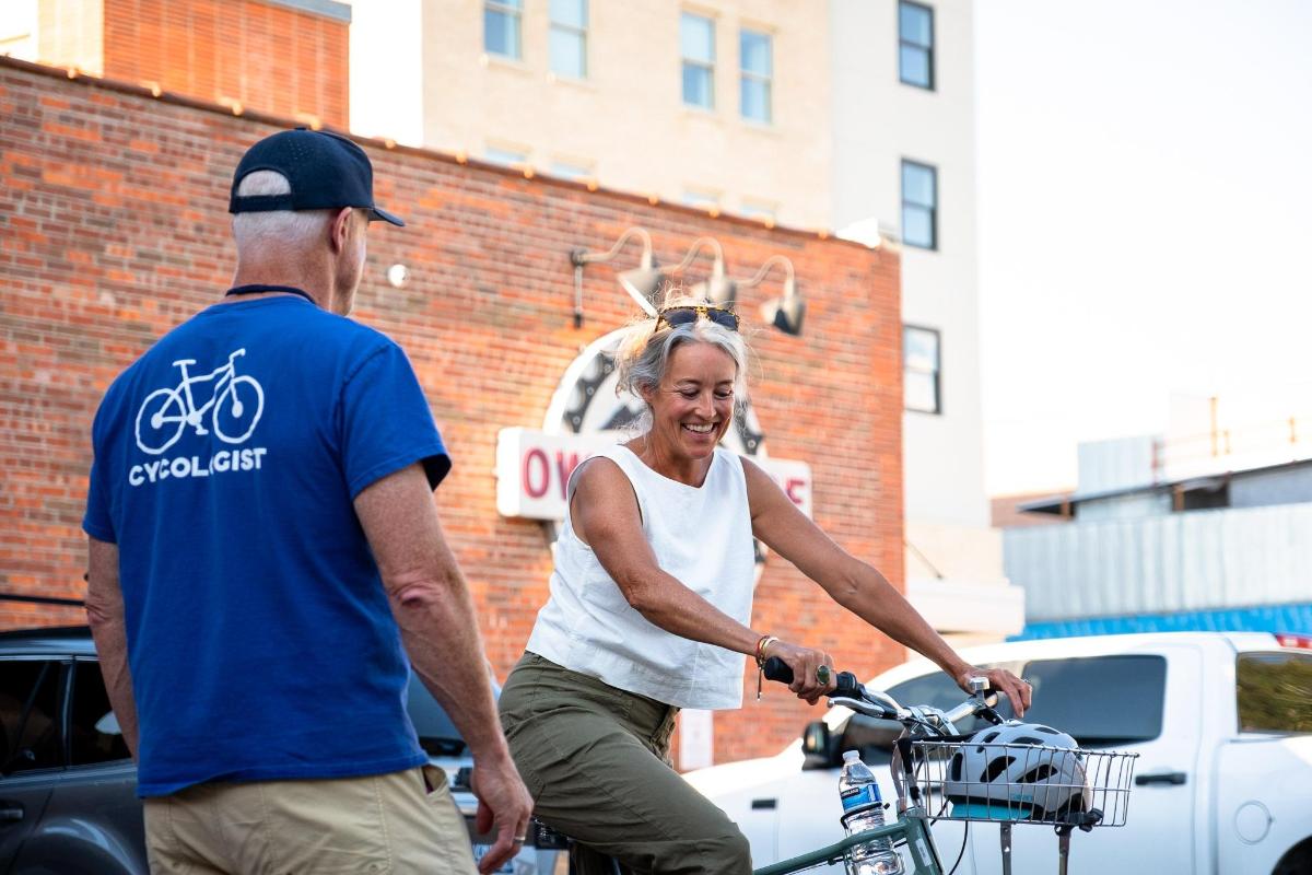 an older woman riding a bike next to a man