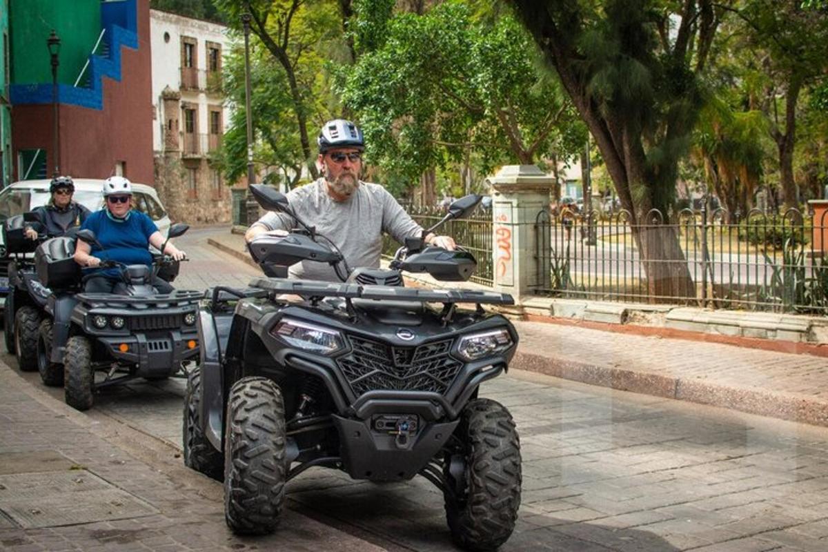 two people riding on atvs on a street