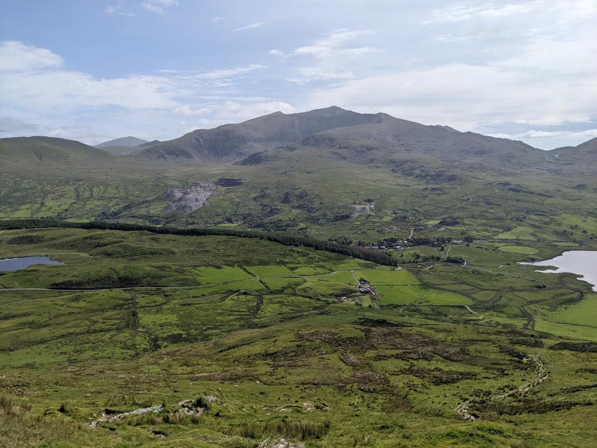 an aerial view of a green field and mountains