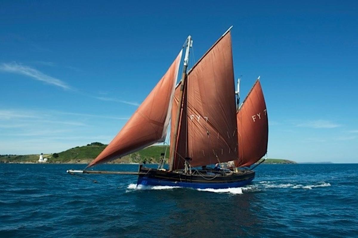 a boat with an orange sail in the water