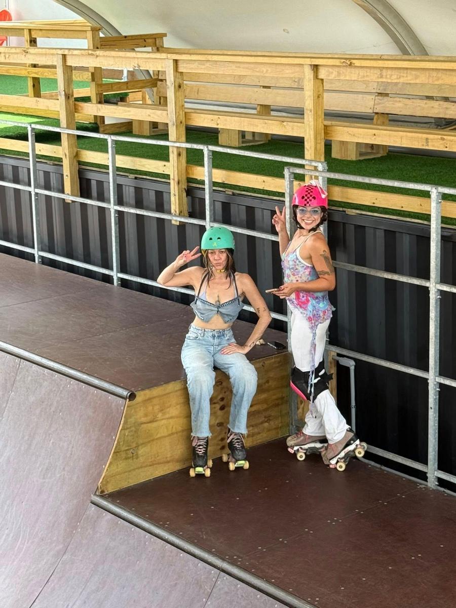 two girls are sitting on a platform with skateboards