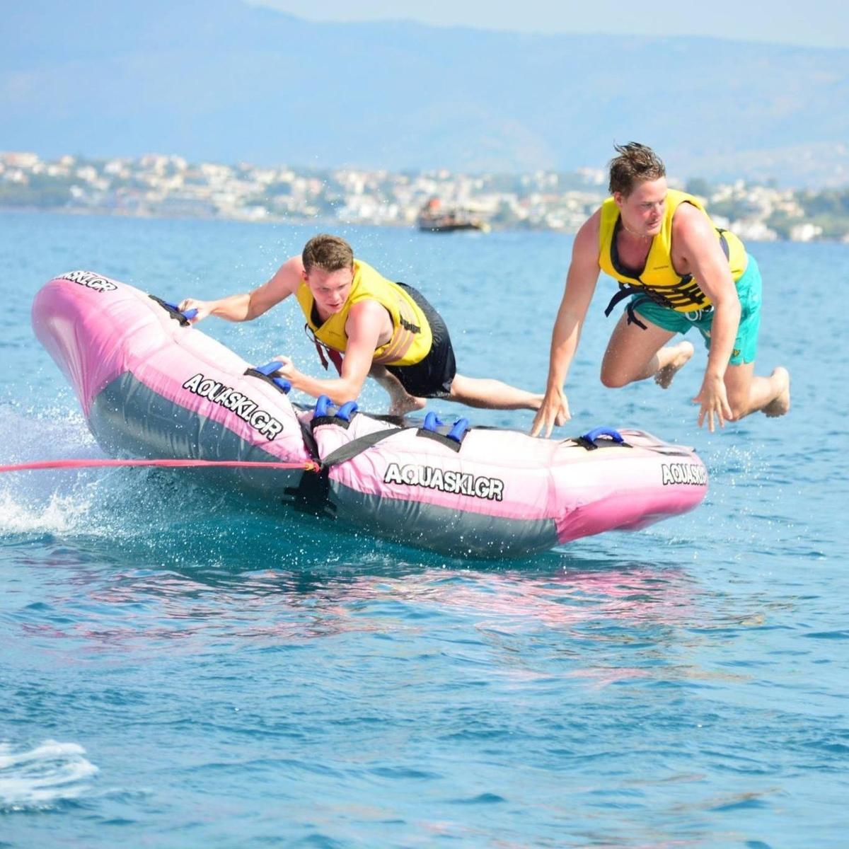 two men jumping off of a pink raft in the water