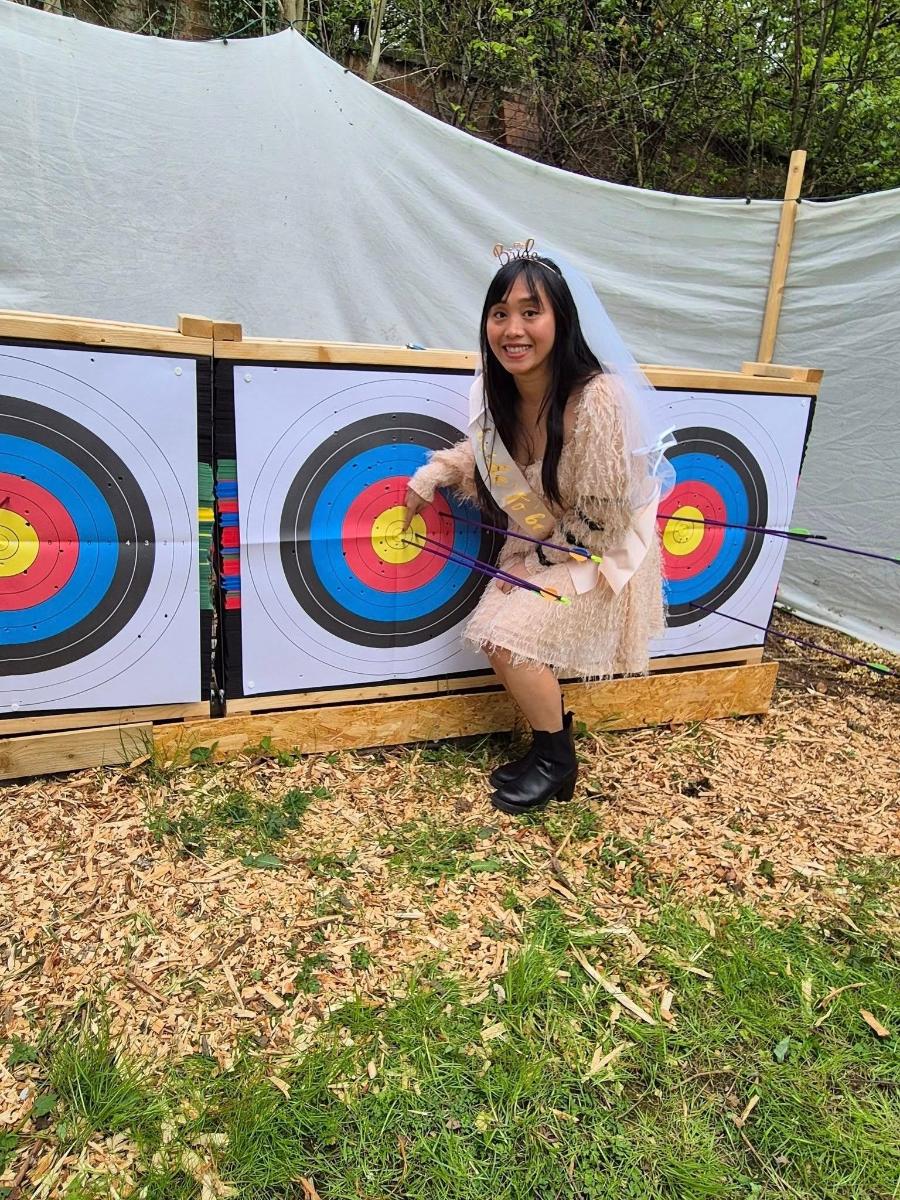 a woman holding a bow and arrow next to a target