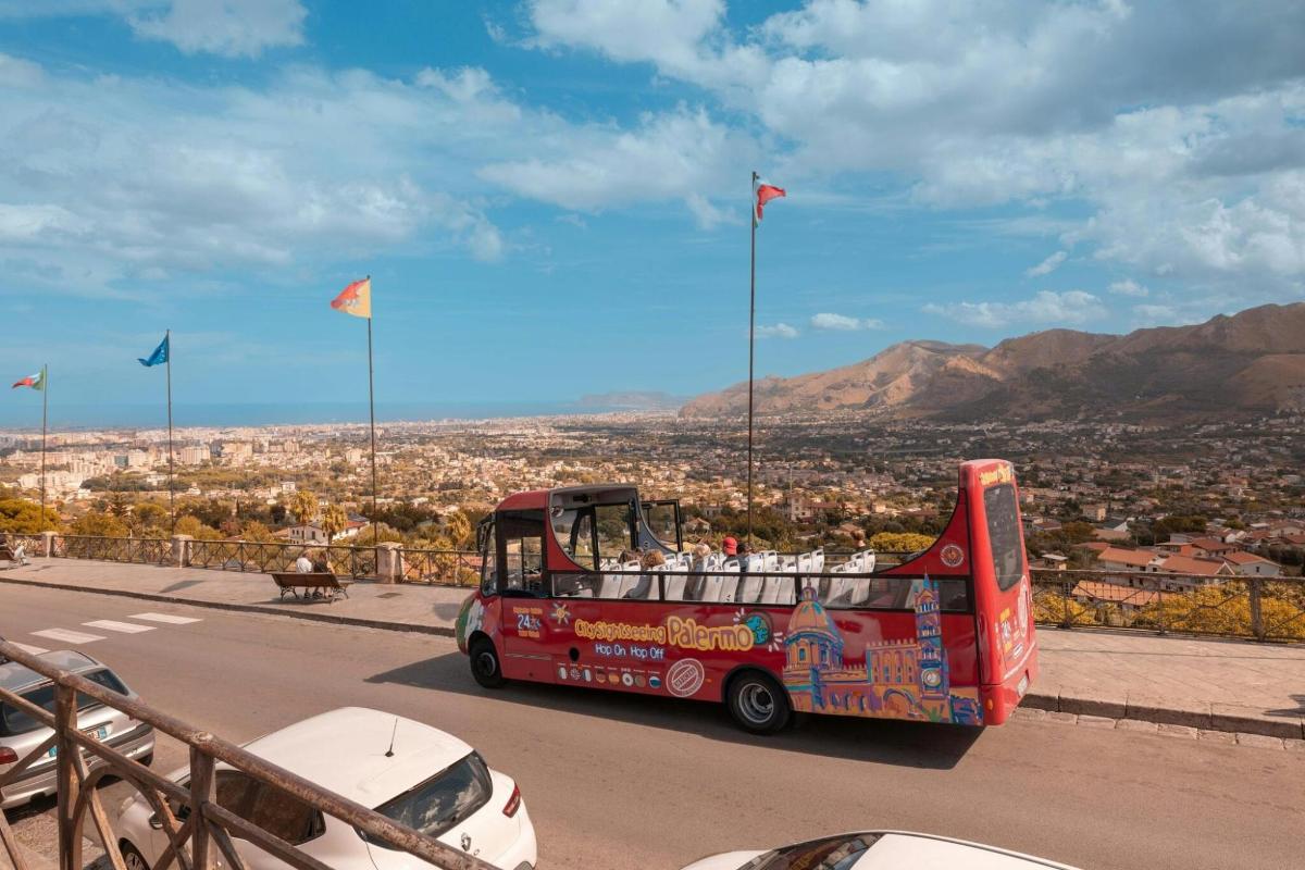 a red bus driving down a road with flags