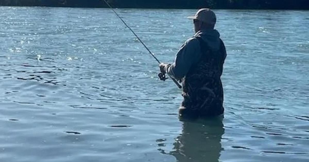 a man standing in the water holding a fishing rod