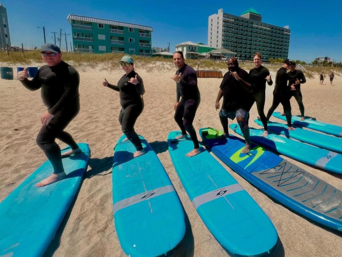 a group of men standing on surfboards on the beach