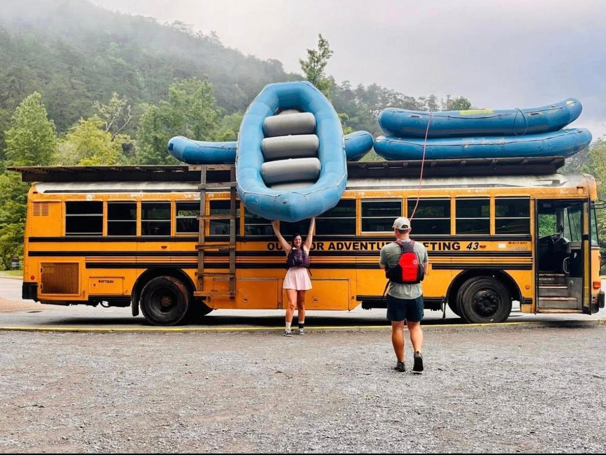 two people are standing in front of a school bus