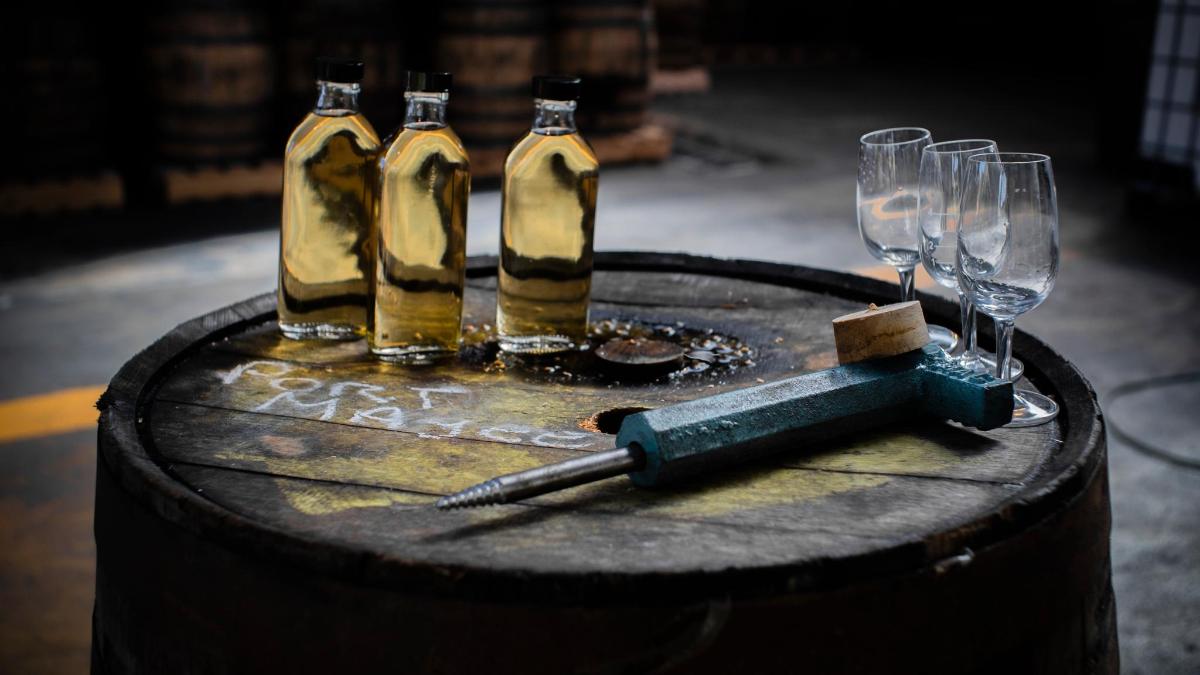 three bottles of wine and wine glasses on a barrel