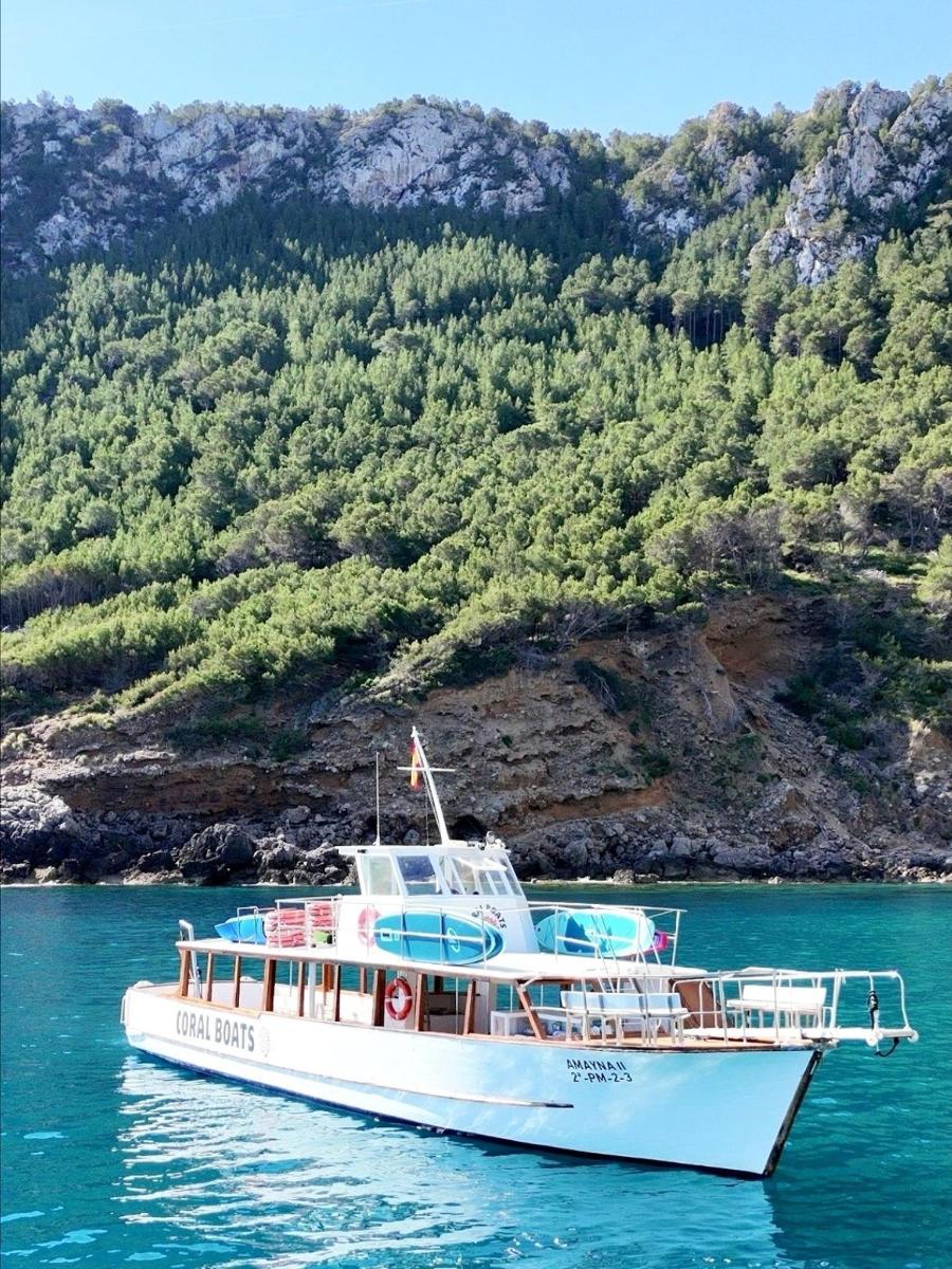 a white boat in the water near a mountain