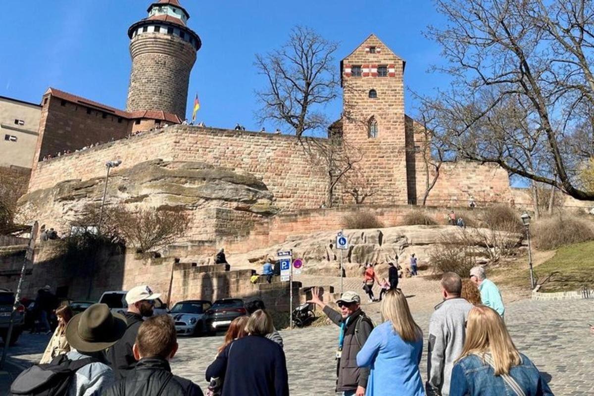 a group of people standing outside of a castle with a lighthouse