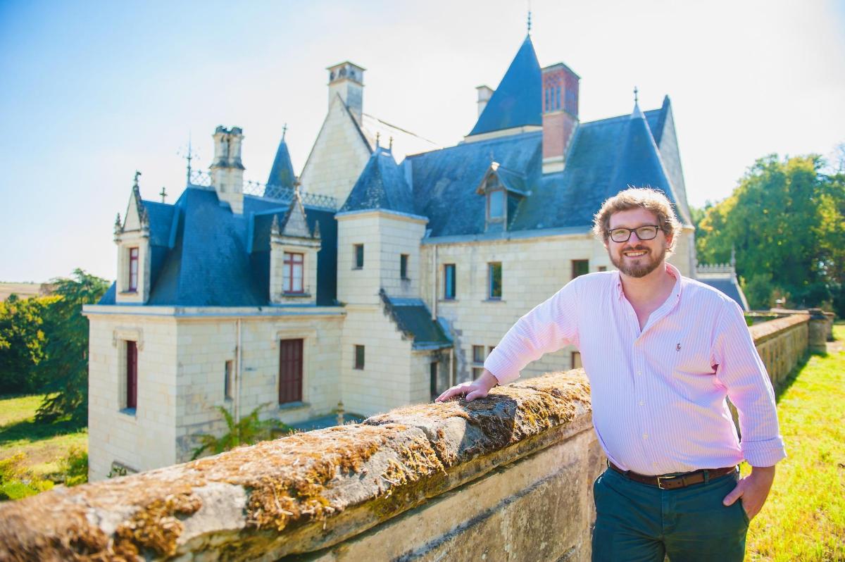 a man leaning against a wall in front of a castle