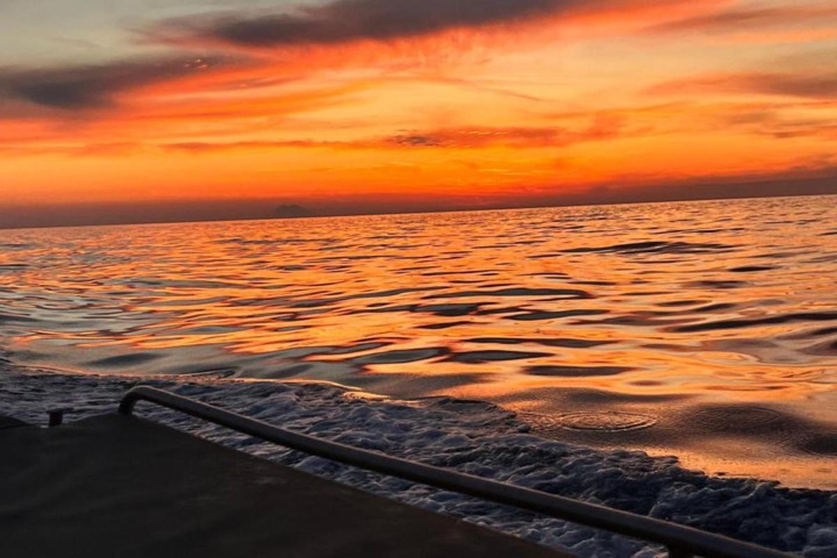 a boat in the ocean with a sunset