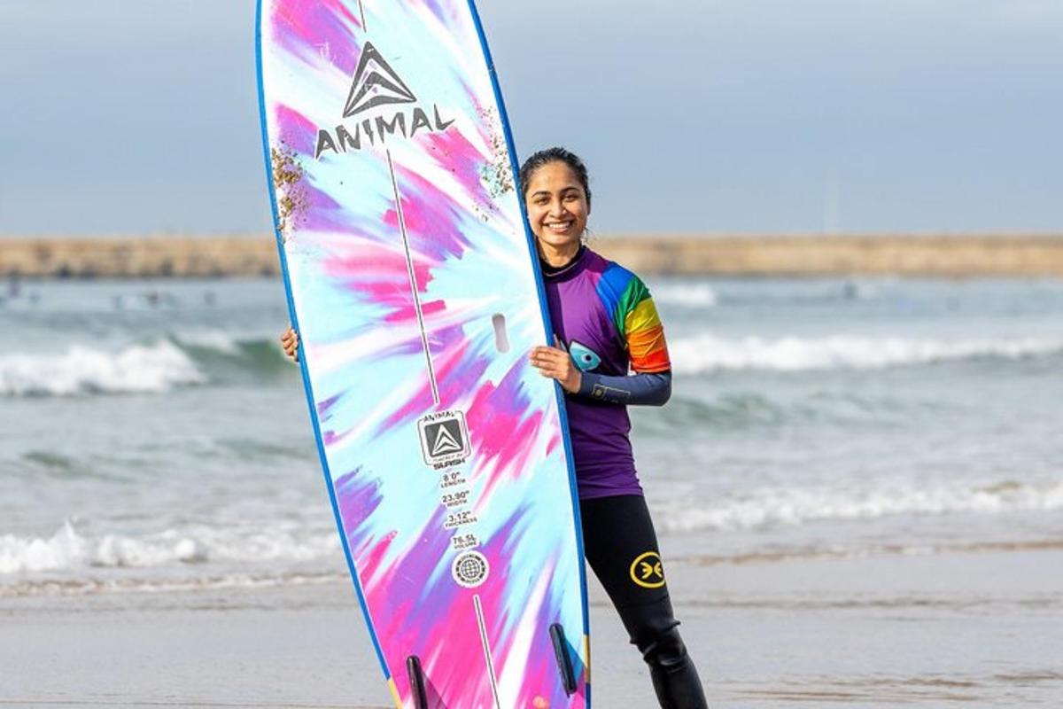 a woman standing on the beach holding a surfboard