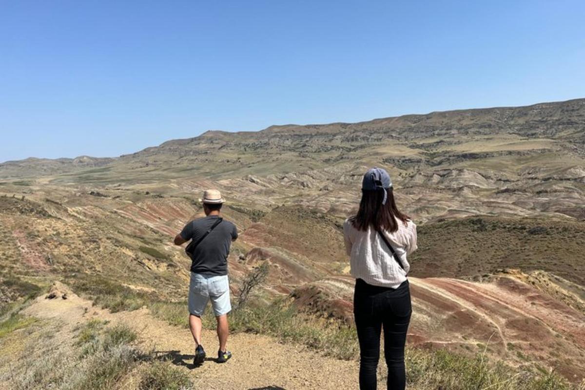a man and a woman standing on a hill looking up at a mountain