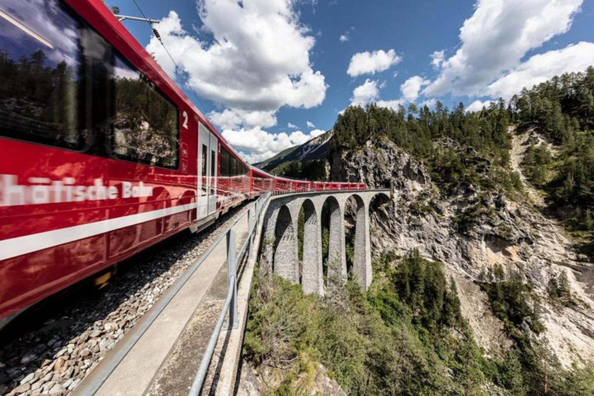 a red train on a bridge over a mountain