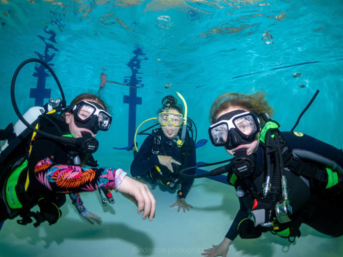 a group of three people wearing diving gear in the water